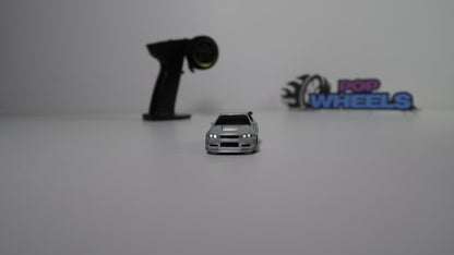Small toy car with remote control and 'Pop Wheels' branding on a white background